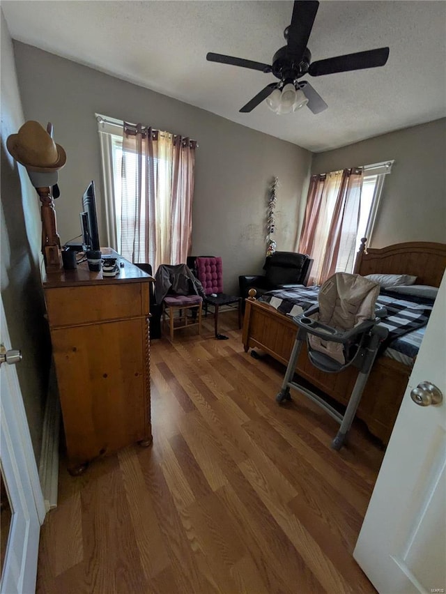 bedroom with a textured ceiling, light wood finished floors, and a ceiling fan