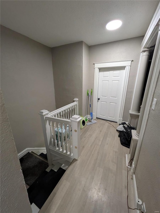 interior space with a textured wall, a textured ceiling, baseboards, and wood finished floors