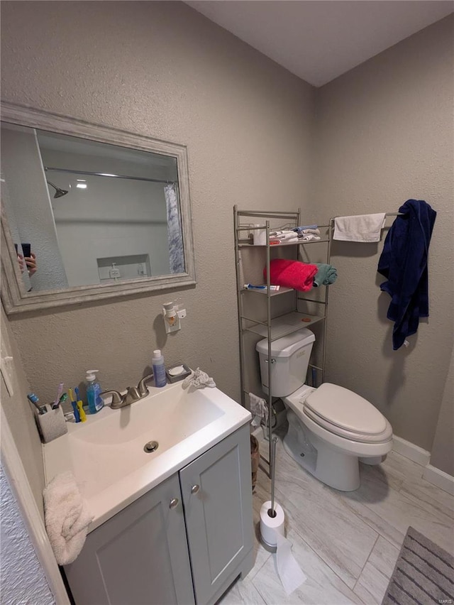 full bathroom with baseboards, a textured wall, toilet, marble finish floor, and vanity