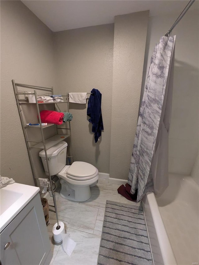 bathroom featuring marble finish floor, shower / bathtub combination with curtain, toilet, vanity, and baseboards