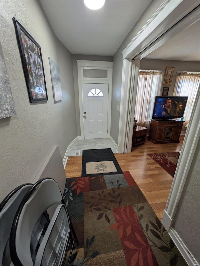 foyer featuring baseboards and wood finished floors