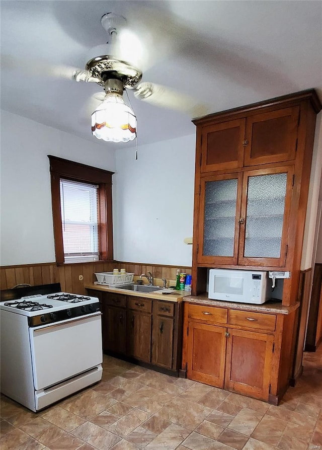 kitchen with sink, white appliances, and wooden walls