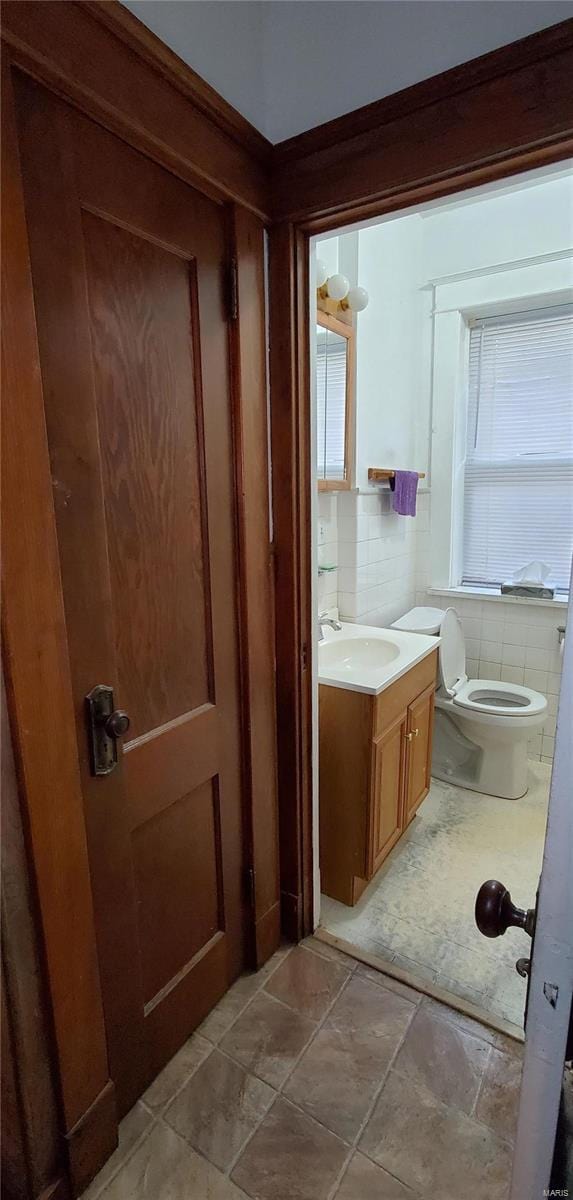 bathroom with vanity, toilet, tile walls, and backsplash