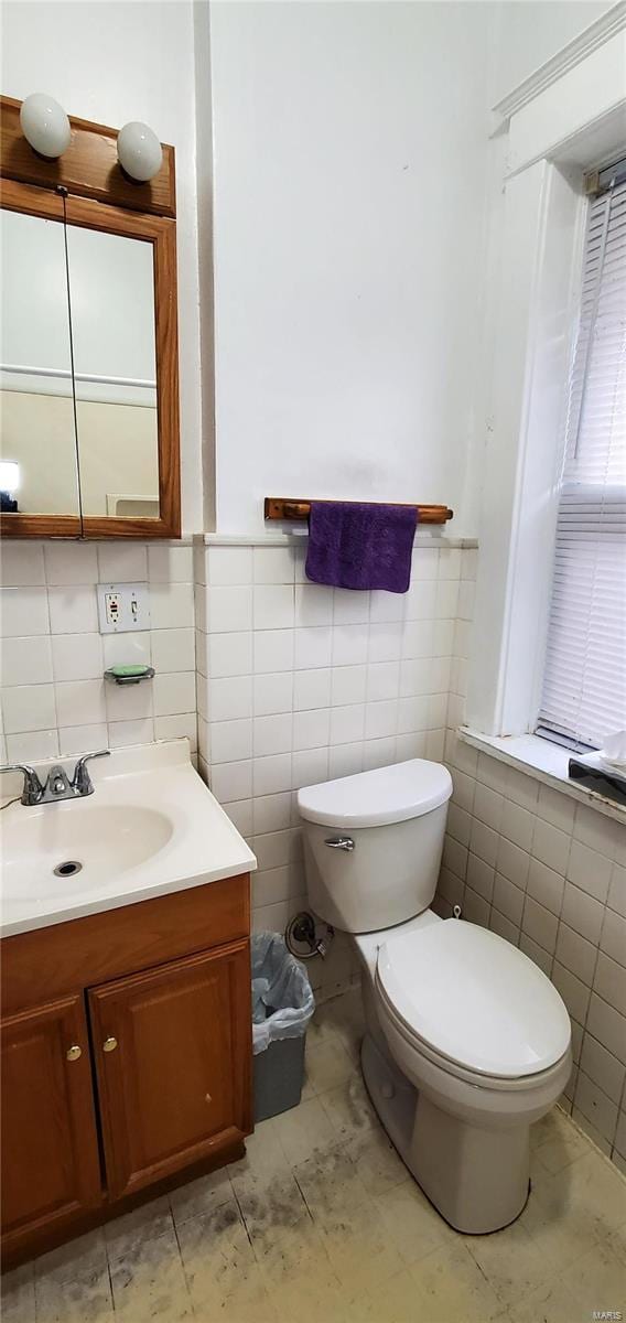 bathroom with vanity, toilet, and tile walls