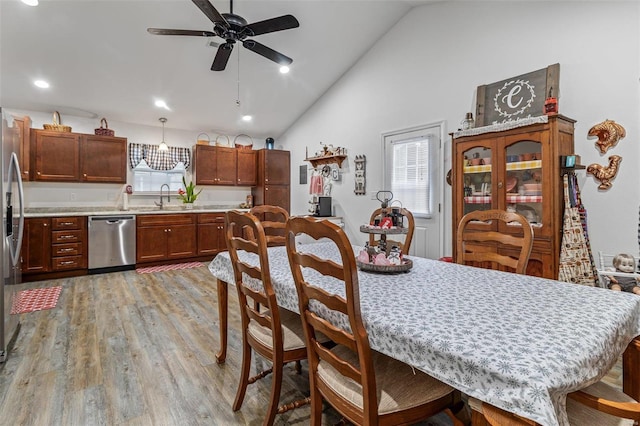 dining space with ceiling fan, lofted ceiling, sink, and light hardwood / wood-style floors