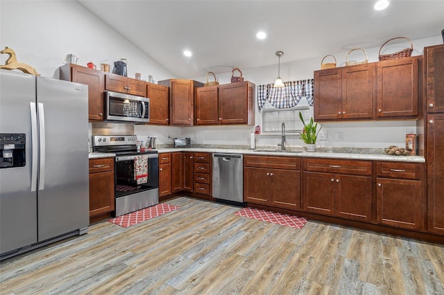 kitchen with lofted ceiling, sink, decorative light fixtures, light hardwood / wood-style flooring, and stainless steel appliances