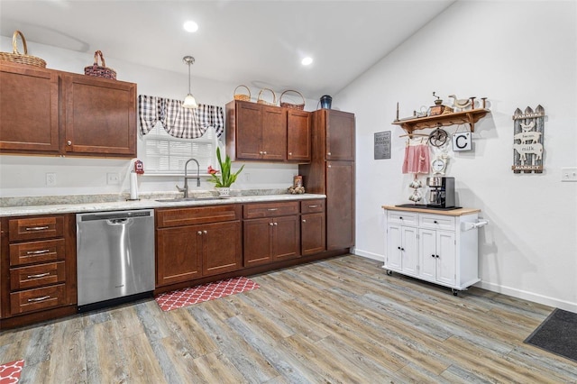 kitchen with lofted ceiling, sink, decorative light fixtures, light hardwood / wood-style flooring, and stainless steel dishwasher