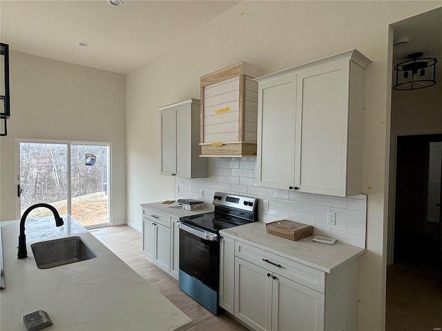 kitchen featuring sink, stainless steel range with electric cooktop, wall chimney exhaust hood, and white cabinets