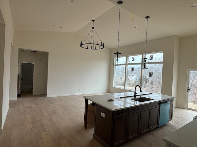 kitchen with decorative light fixtures, an island with sink, sink, stainless steel dishwasher, and light wood-type flooring