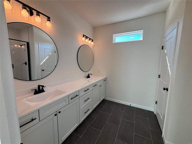 full bathroom with a sink, baseboards, a shower with door, and double vanity