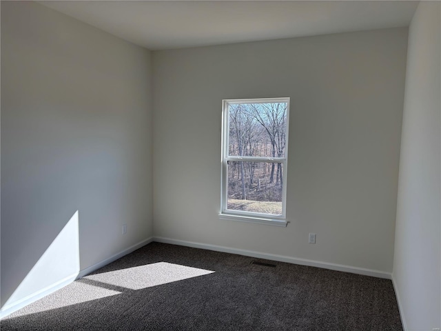 spare room with visible vents, baseboards, and dark carpet