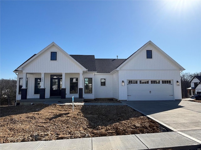 modern farmhouse with brick siding, board and batten siding, concrete driveway, covered porch, and an attached garage