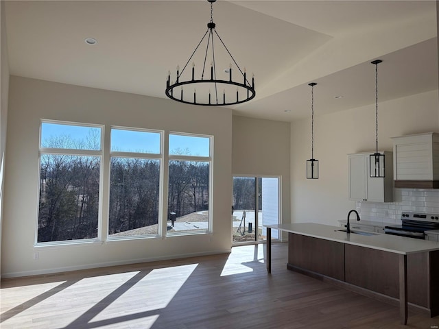 kitchen with dark wood finished floors, light countertops, decorative backsplash, stainless steel range with electric stovetop, and a sink