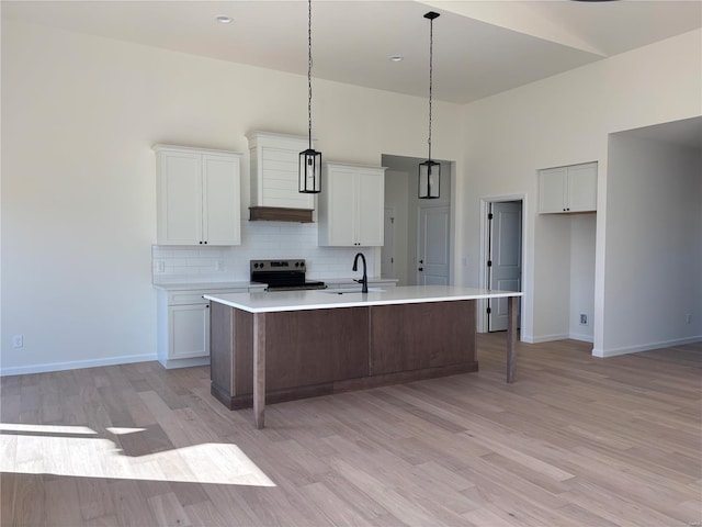 kitchen featuring premium range hood, a sink, decorative backsplash, electric stove, and a towering ceiling