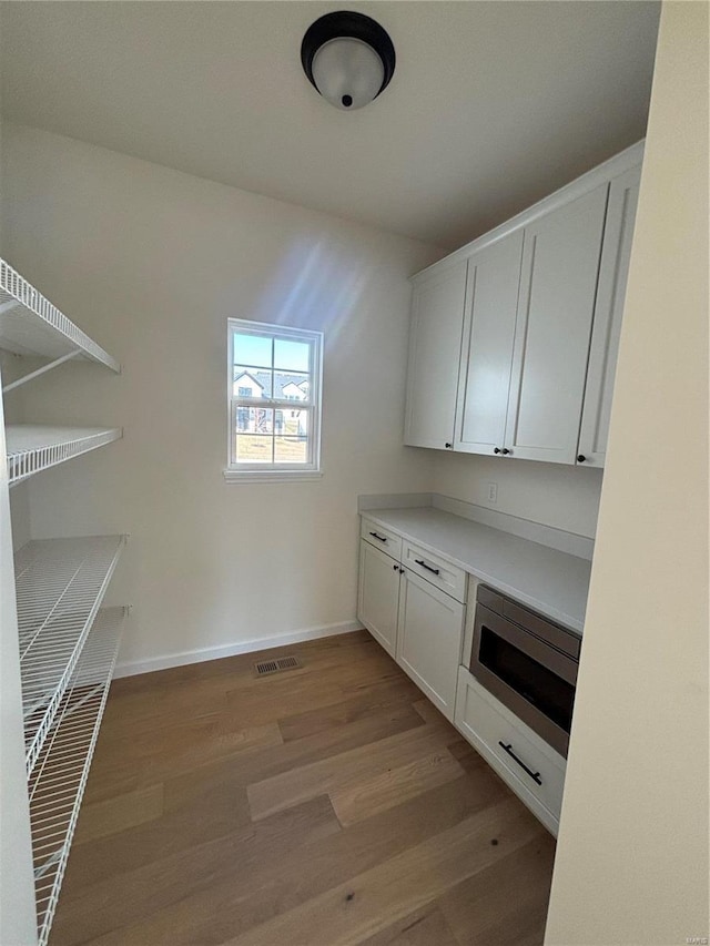 interior space with wood finished floors, visible vents, and baseboards