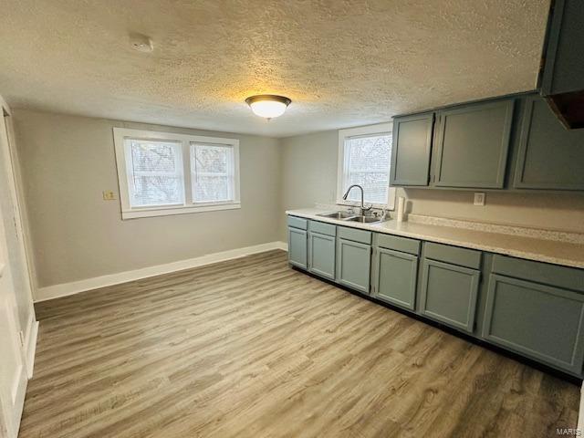 kitchen with green cabinets, light hardwood / wood-style floors, sink, and a textured ceiling