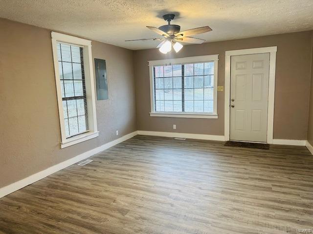 entrance foyer featuring hardwood / wood-style flooring, ceiling fan, electric panel, and a textured ceiling