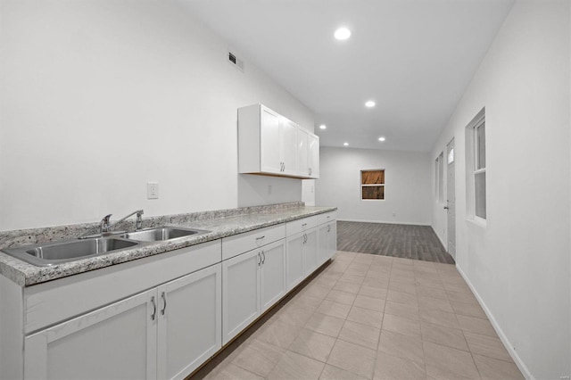 kitchen featuring light countertops, a sink, white cabinetry, and recessed lighting