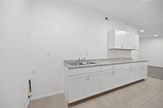 kitchen featuring light countertops, visible vents, white cabinetry, a sink, and baseboards