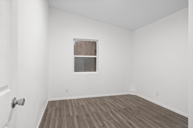 spare room featuring baseboards and dark wood-type flooring