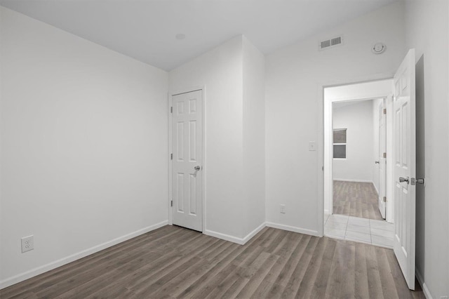 spare room with wood finished floors, visible vents, and baseboards