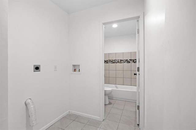 bathroom with a tub to relax in, toilet, baseboards, and tile patterned floors