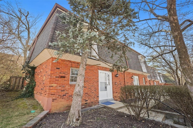 view of front of home featuring mansard roof, brick siding, and roof with shingles