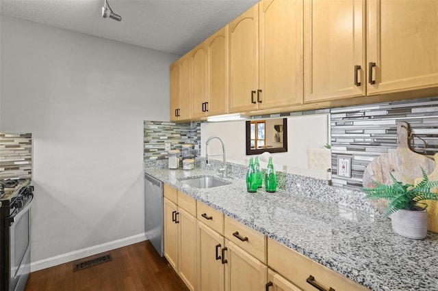 kitchen with light brown cabinets, dishwasher, gas stove, and a sink