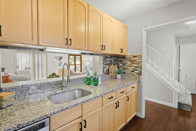 kitchen with light brown cabinetry, a sink, light stone counters, dishwashing machine, and dark wood-style flooring