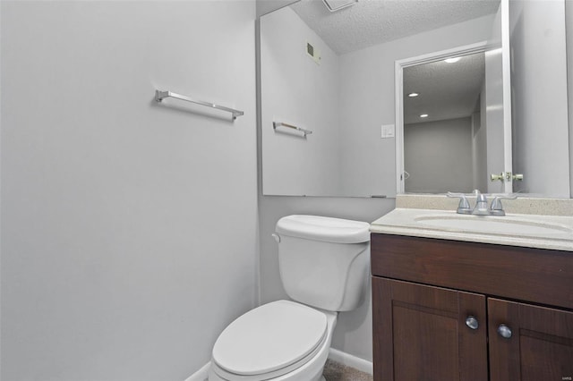 half bathroom featuring vanity, toilet, baseboards, and a textured ceiling