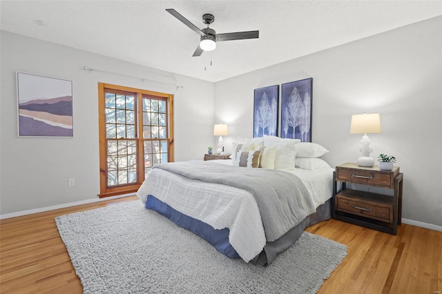 bedroom with a ceiling fan, baseboards, and light wood-type flooring