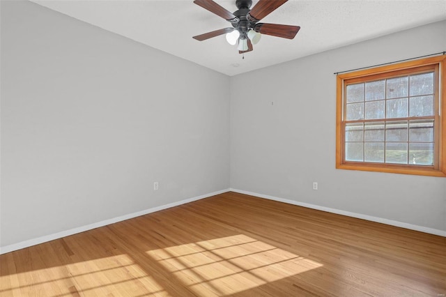 unfurnished room featuring a ceiling fan, wood finished floors, and baseboards