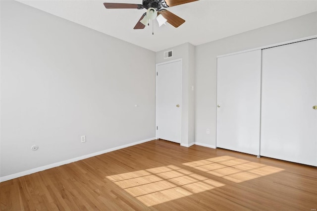 unfurnished bedroom featuring a ceiling fan, wood finished floors, visible vents, baseboards, and a closet