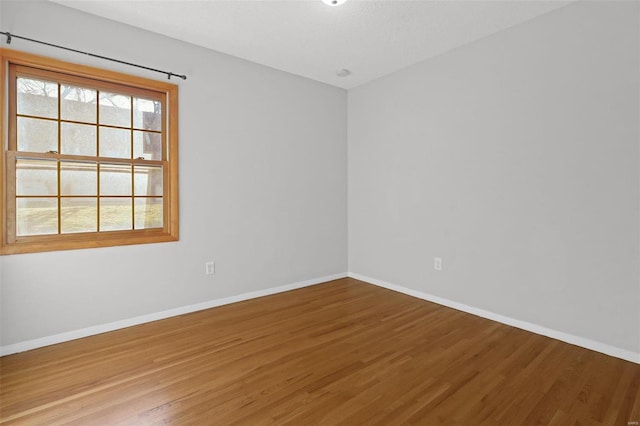 spare room with wood finished floors, baseboards, and a wealth of natural light