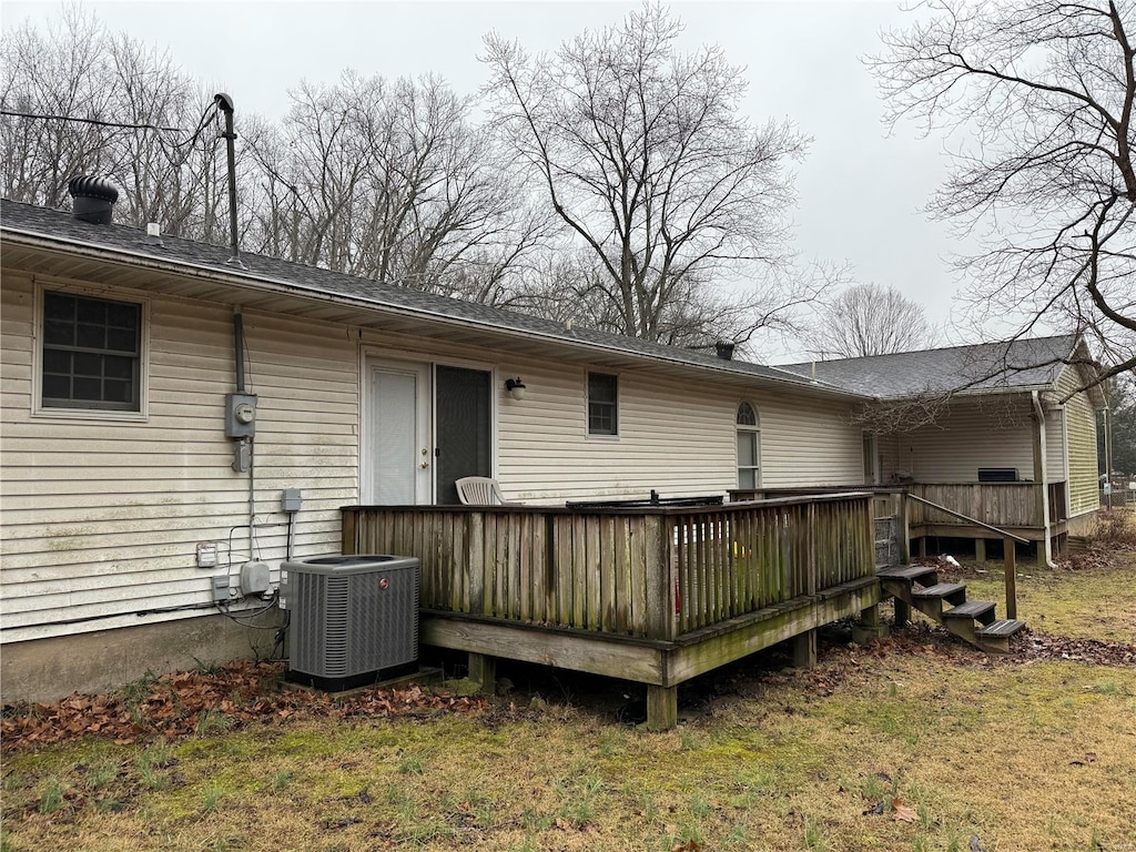 rear view of property featuring a wooden deck, a lawn, and central air condition unit