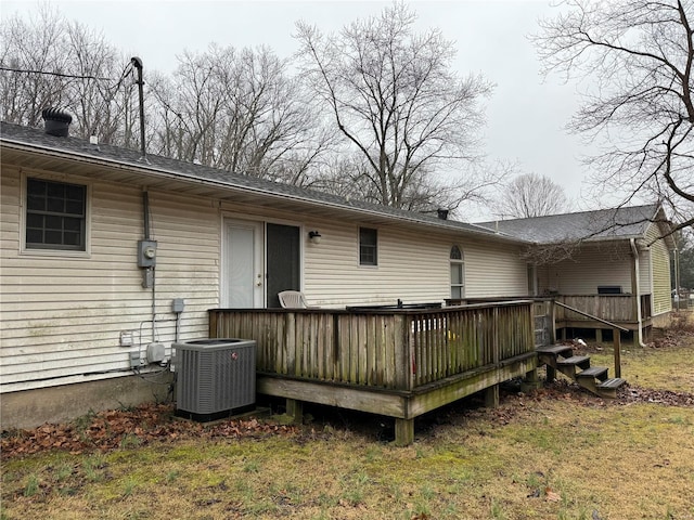 rear view of property featuring a wooden deck, a lawn, and central air condition unit