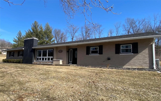 ranch-style house with a chimney, a front lawn, and brick siding