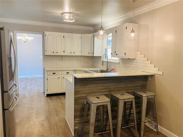 kitchen featuring a breakfast bar area, stainless steel refrigerator with ice dispenser, a sink, and white cabinetry