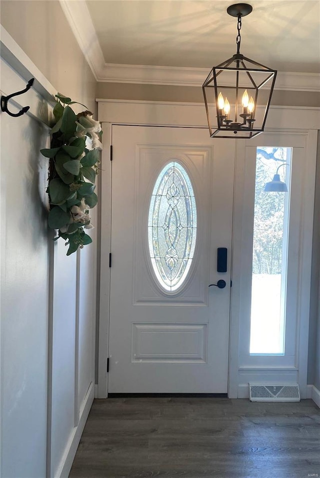 entrance foyer featuring visible vents, crown molding, wood finished floors, and a notable chandelier