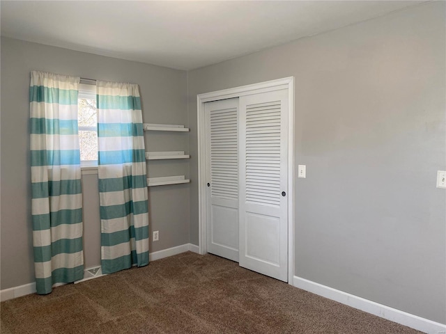 unfurnished bedroom with baseboards, carpet flooring, and a closet