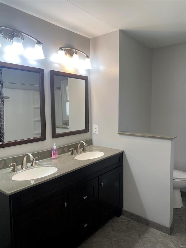 full bathroom featuring double vanity, a sink, tile patterned floors, and toilet