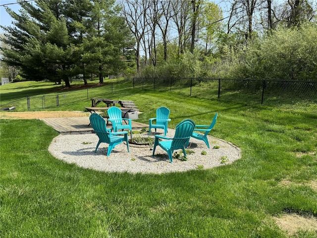view of play area featuring a lawn, a fire pit, and fence
