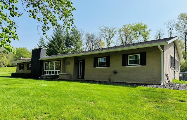 ranch-style home with central air condition unit, brick siding, a chimney, and a front lawn