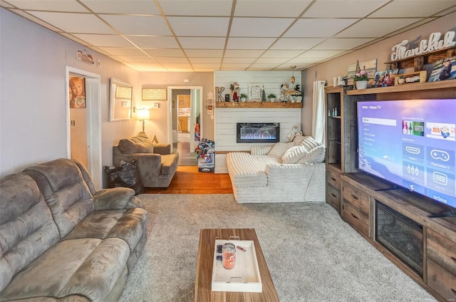 carpeted living room featuring a drop ceiling