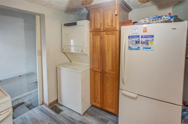 laundry area with stacked washer and dryer and light wood-type flooring