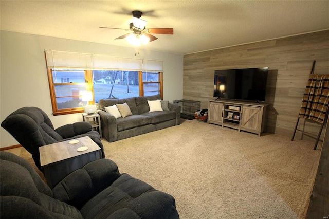 living room with ceiling fan, wooden walls, carpet, and a textured ceiling