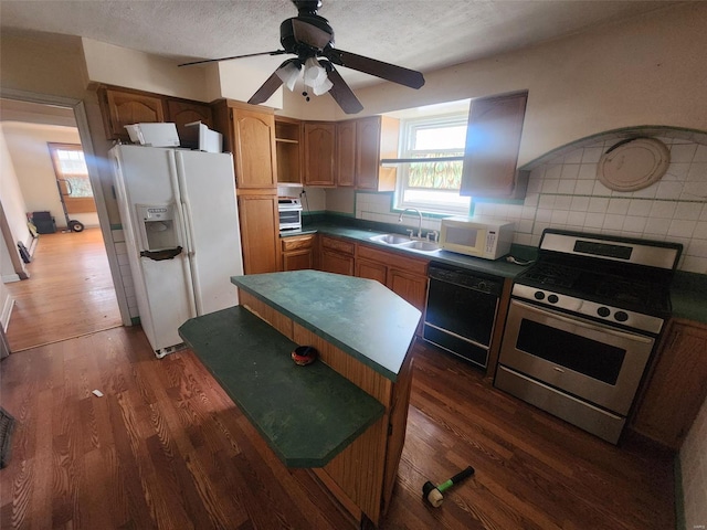 kitchen with sink, backsplash, white appliances, dark wood-type flooring, and a textured ceiling