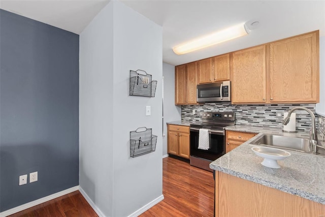 kitchen featuring sink, backsplash, dark hardwood / wood-style flooring, stainless steel appliances, and light stone countertops