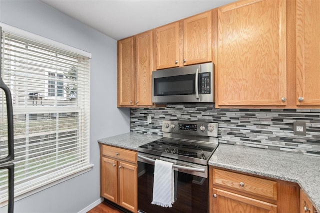 kitchen with tasteful backsplash, light stone countertops, and appliances with stainless steel finishes