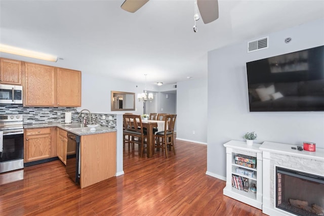 kitchen featuring decorative light fixtures, sink, backsplash, kitchen peninsula, and stainless steel appliances